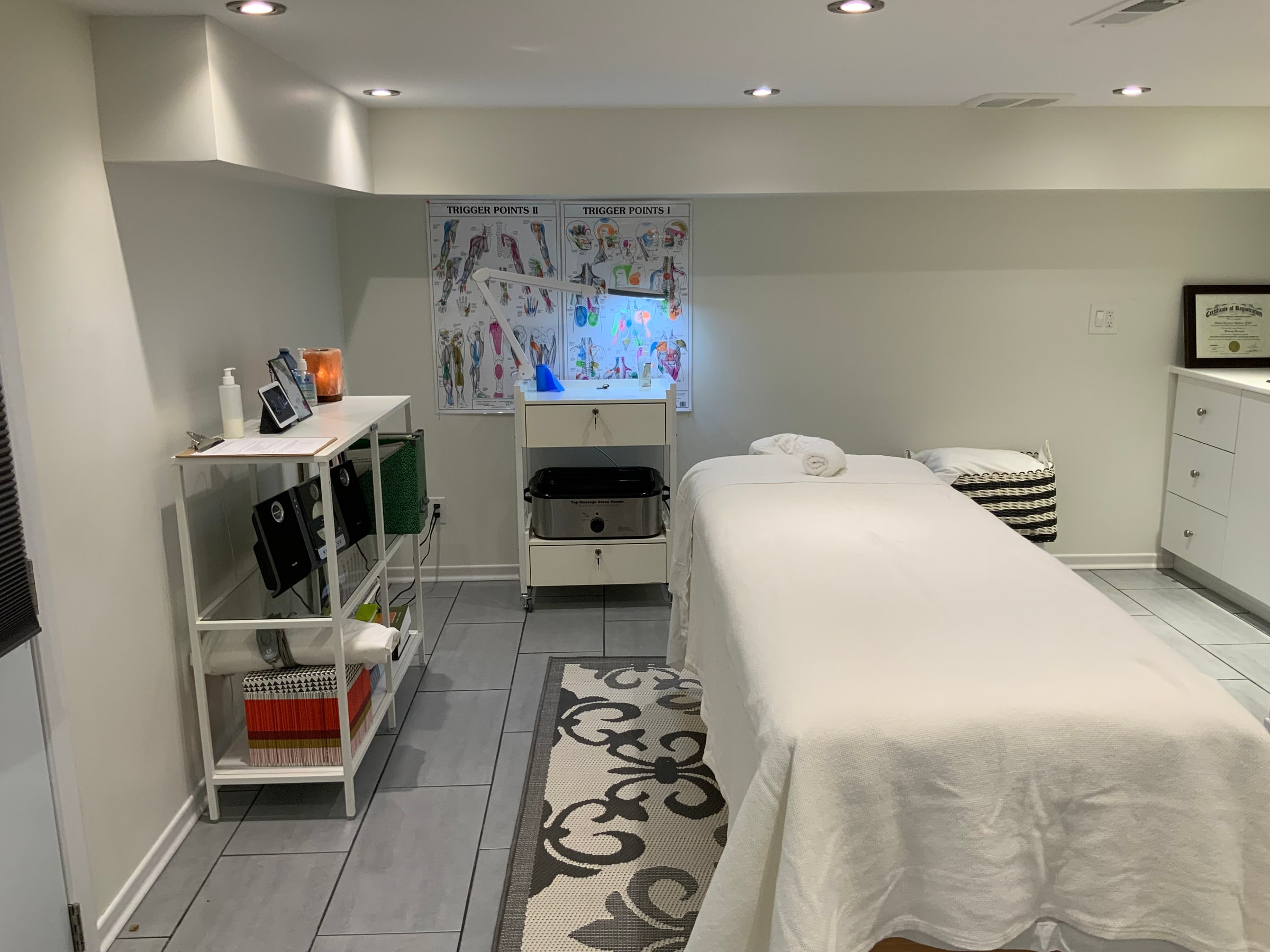 Massage treatment room at Cypri Massage Therapy in Toronto, with table, towels and trigger point charts