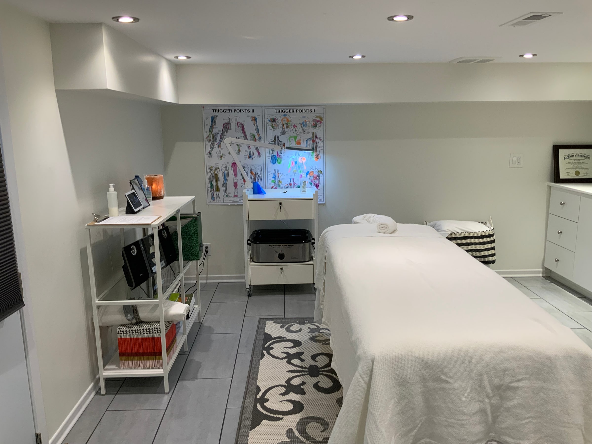 Massage therapy room with supplies shelf and towel warmer at Cypri Massage Therapy, Toronto